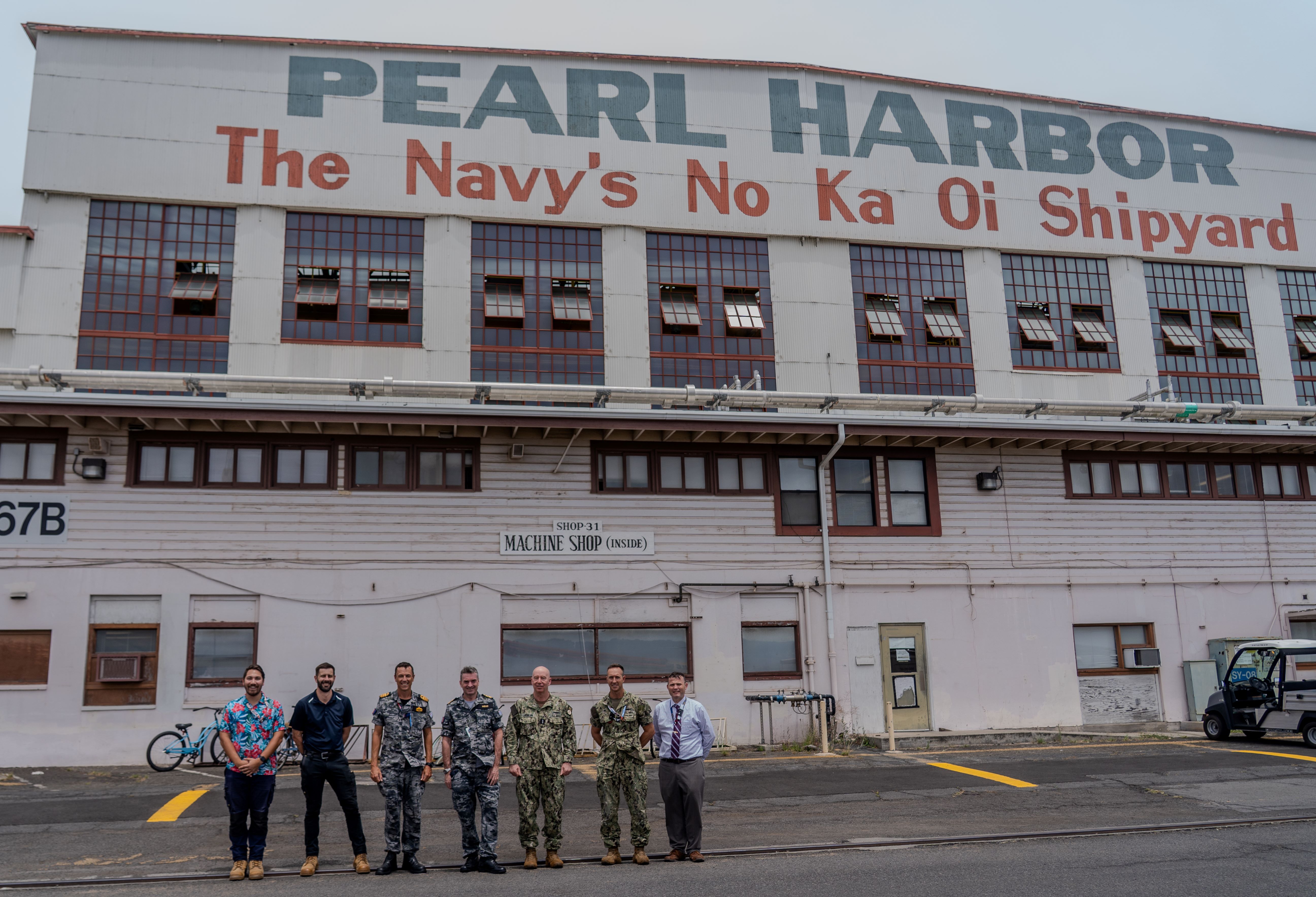 Royal Australian Navy VADM Jonathan Mead, Director-General of the Australian Submarine Agency (centre) and U.S. Navy Adm. William Houston, Director, Naval Nuclear Propulsion Program (centre right), pose for a group photo with Australian sailors, ASC personnel, and U.S. Navy staff outside Machine Shop 31 at Pearl Harbor Naval Shipyard & Intermediate Maintenance Facility.