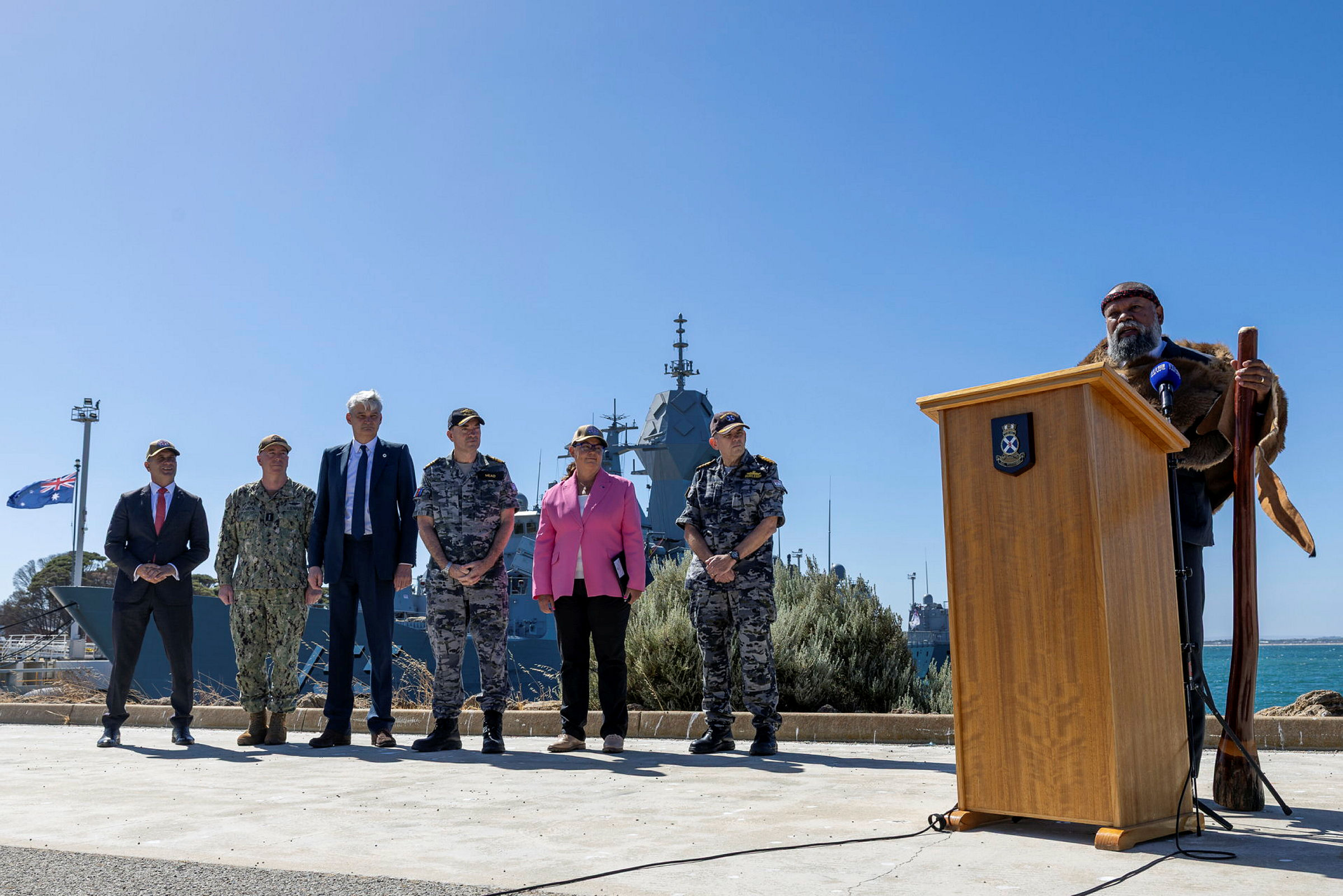 Indigenous Leader, Mr Barry Winmar (far-right), conducts a Welcome to Country for Royal Navy Astute class submarine, HMS Anson, after she arrives at HMAS Stirling, Perth.