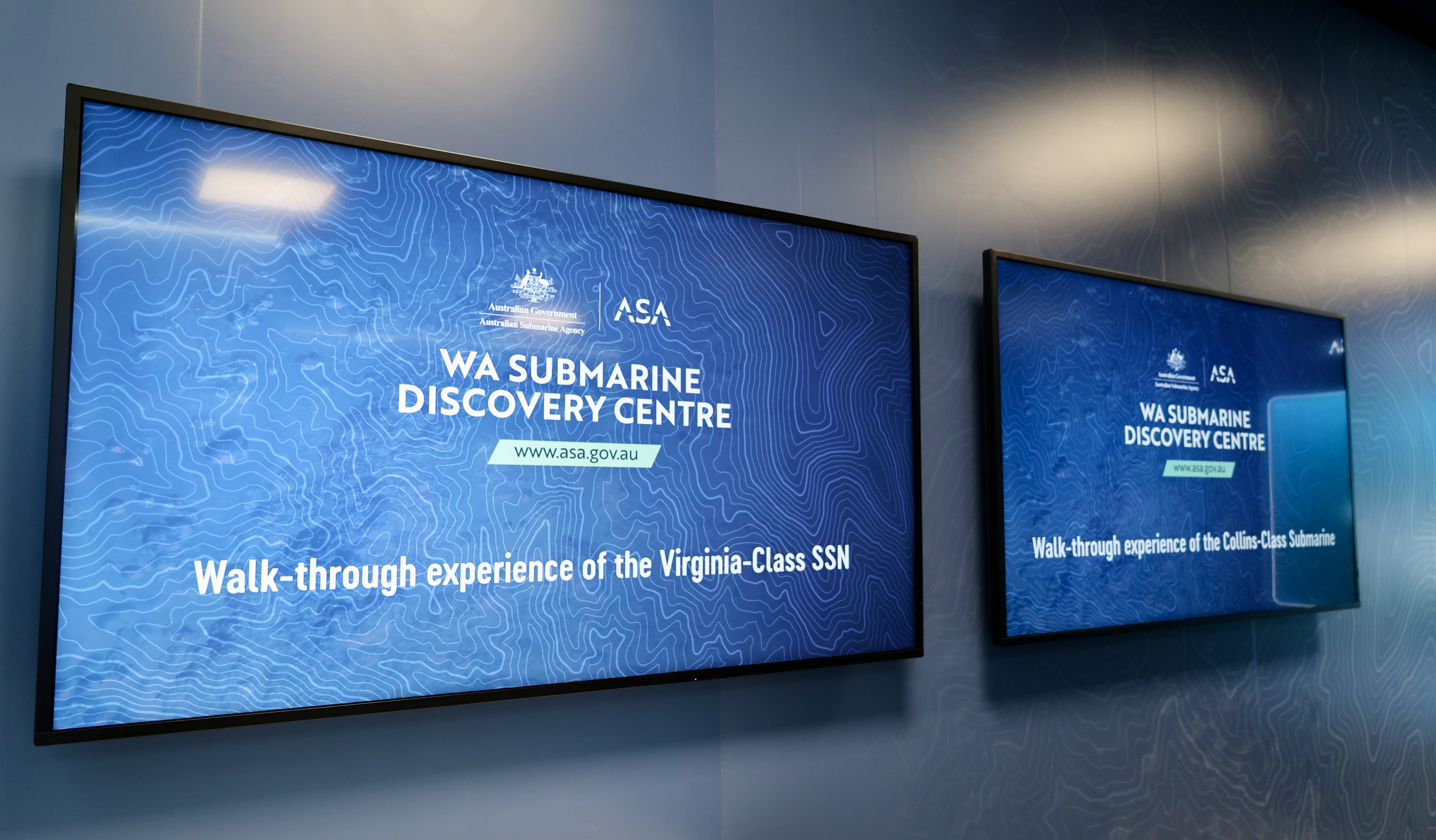 Two wall screens show WA Submarine Discovery Centre info about submarine walk through experiences.