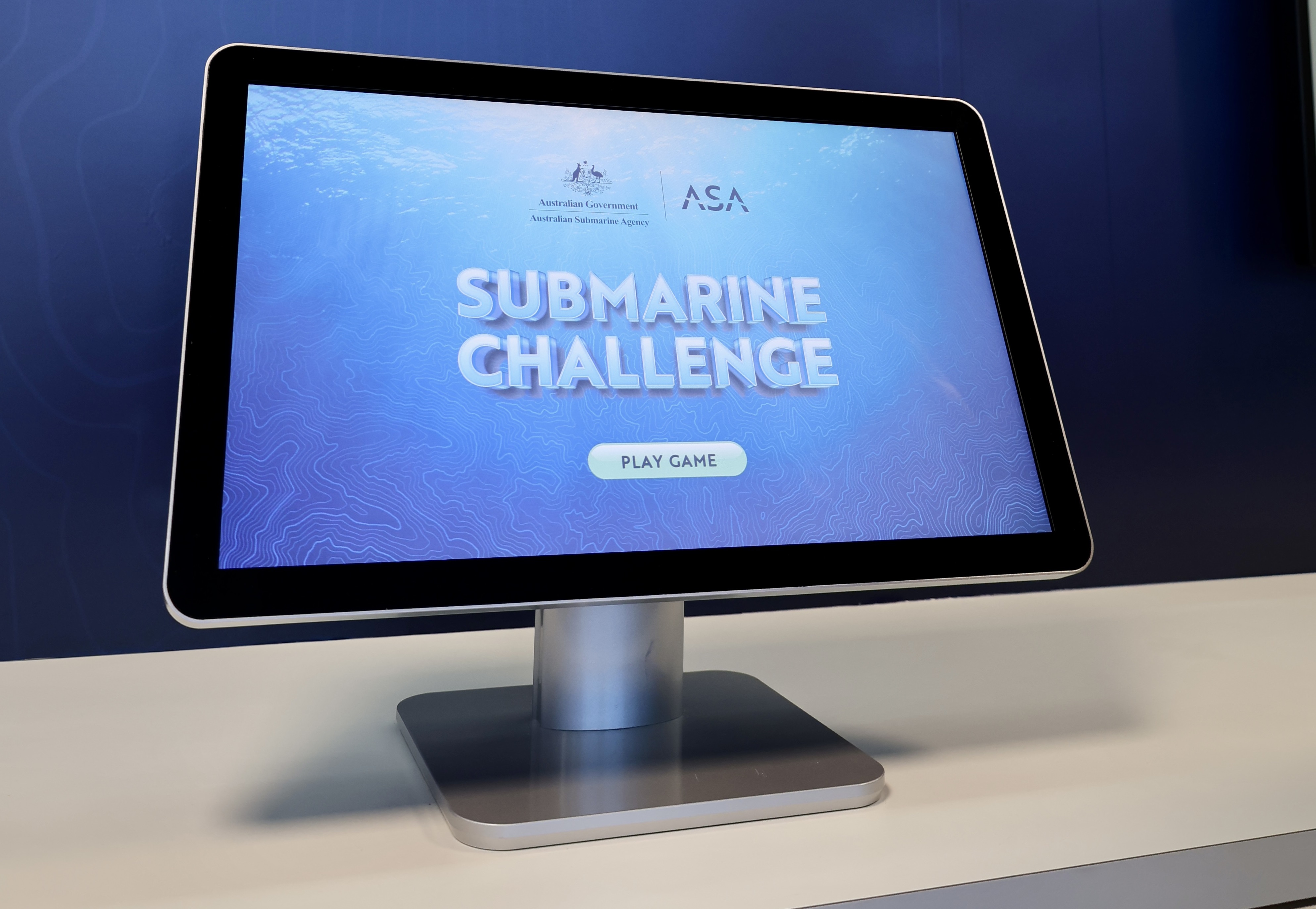 Touch screen shows Submarine Challenge game with play button on a blue display at an interactive exhibit.