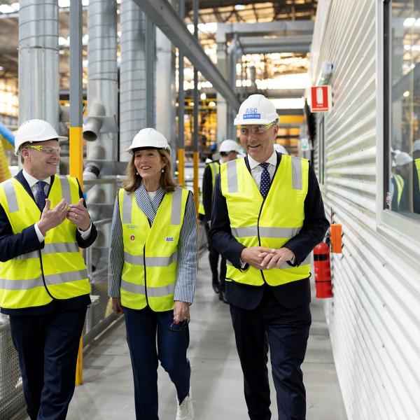 Three people in high-vis vests walking through a factory.